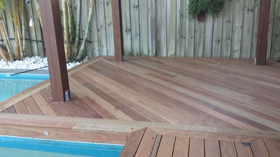 A wooden deck showcasing a pool, bordered by a fence, creating a tranquil outdoor space for relaxation